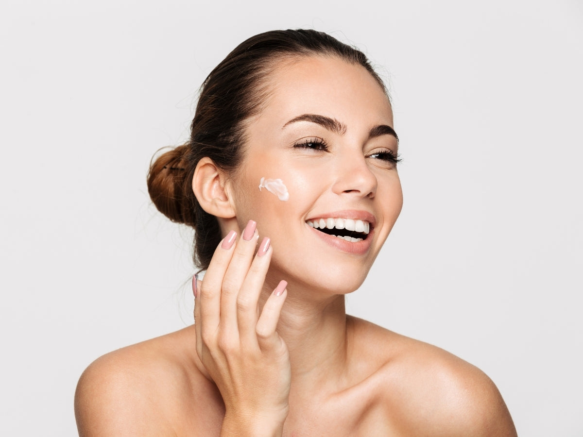 Frau trägt Masquerade von True Story auf und lächelt mit glatter gesunder Haut