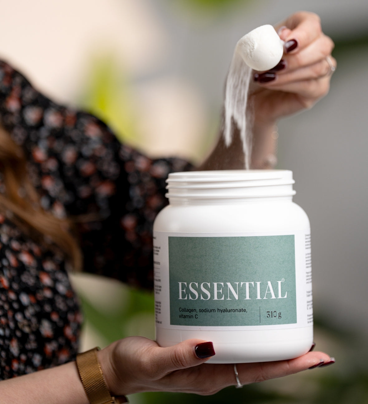 Hand mit Messlöffel nimmt weisses Kollagenpulver aus einer Dose mit der Aufschrift Essential.