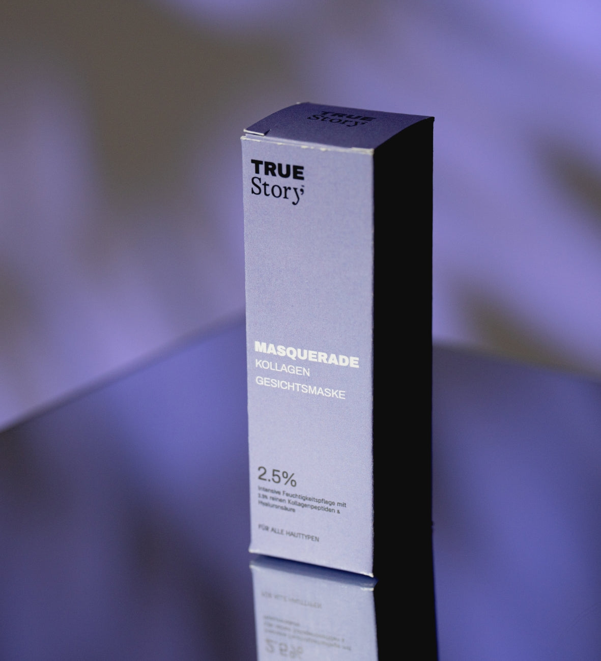 Violette Verpackung der True Story «Masquerade» Kollagen-Gesichtsmaske vor dunklem Hintergrund